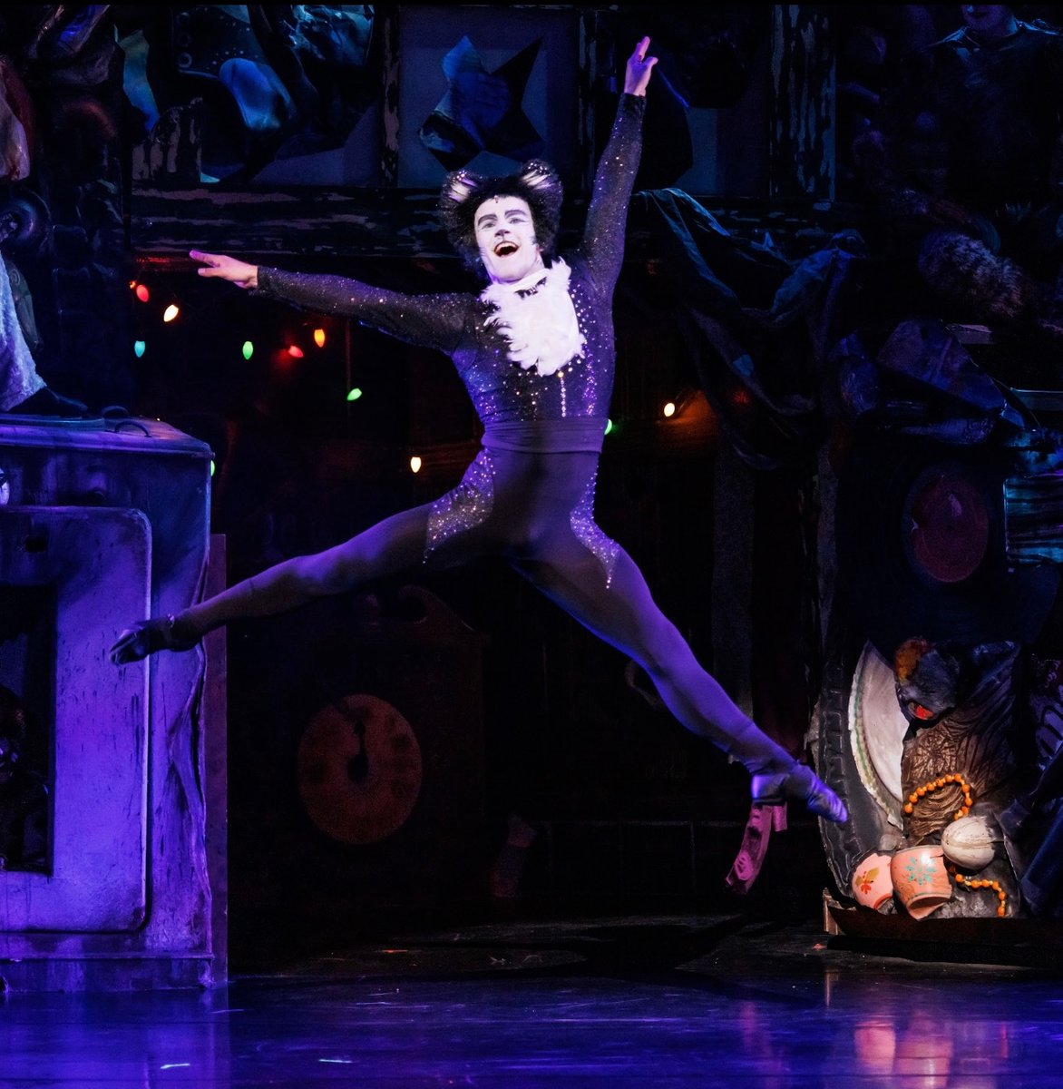 Harry Francis as Mr. Mistoffelees leaping mid-air in his black sparkling costume