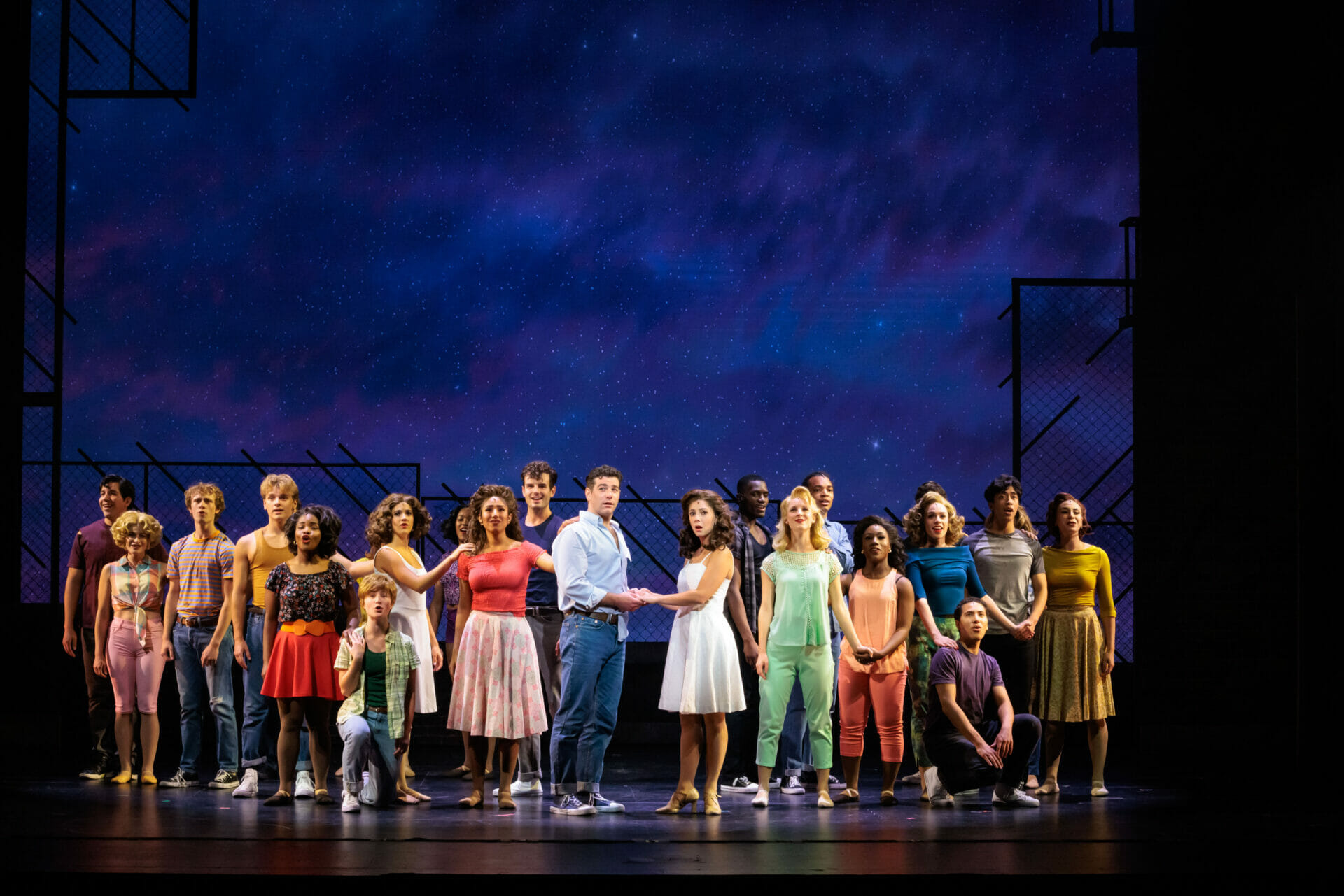 The full company of West Side Story holding hands beneath a starry sky during Somewhere at City Springs Theatre