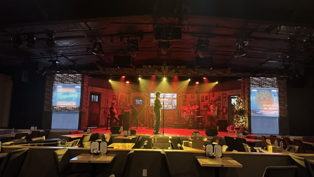The cabaret stage and house tables before a performance, lit warm red.