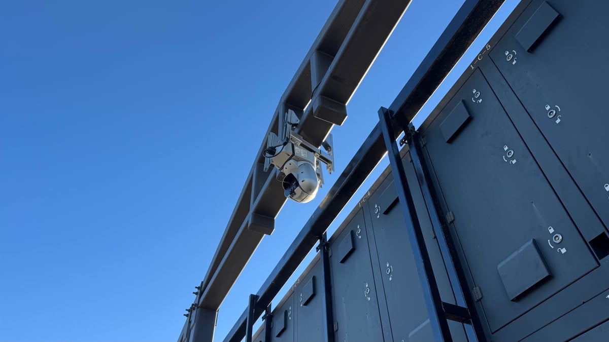 A pan-tilt-zoom camera mounted to the steel structure over one of the competition arenas.