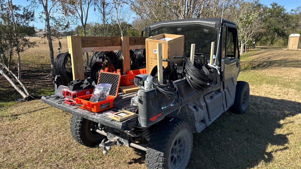 A utility vehicle loaded with cable and road cases, staged to run camera positions across the cross country course.