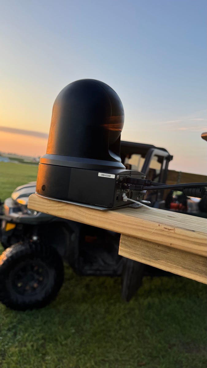 A portable PTZ camera cabled up on a plank mount on the back of a UTV, out on the course at dusk.