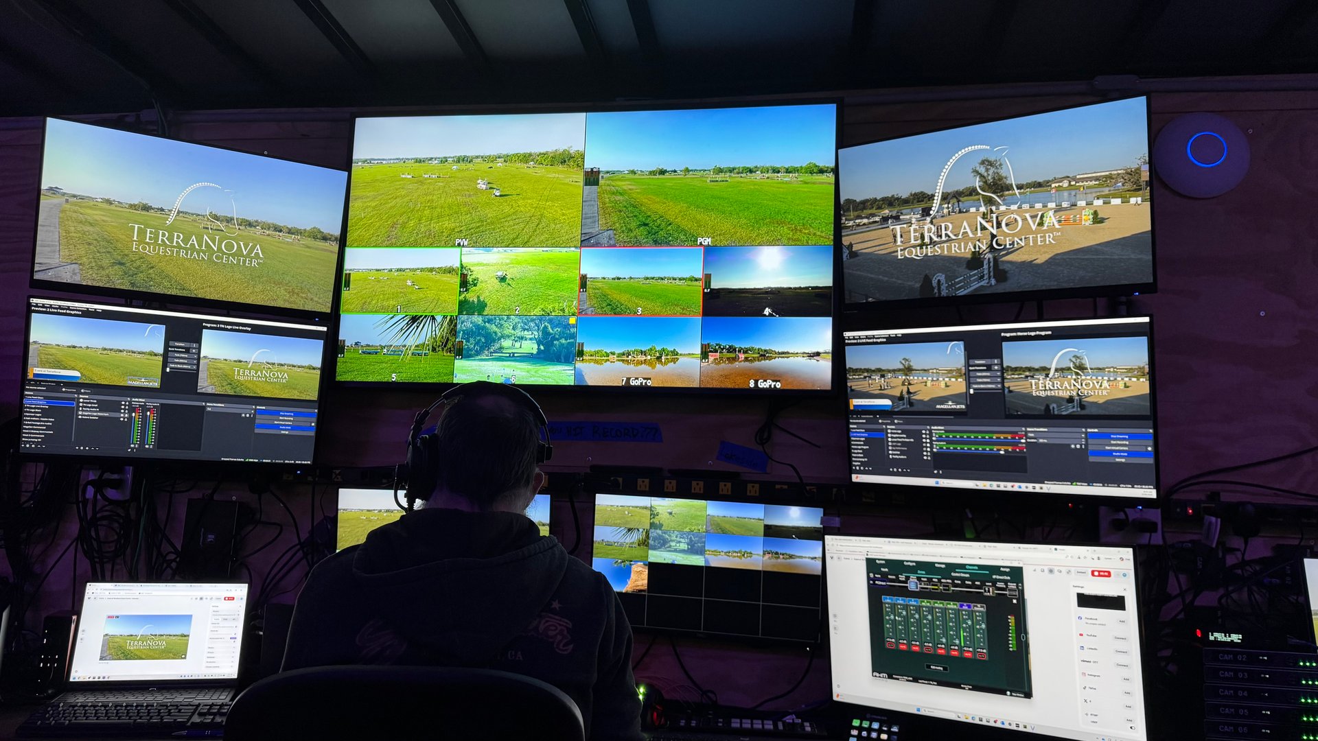 The trailer control room during a show: three large monitors carrying TerraNova-branded program, multiview, and camera feeds, an operator in a headset at the desk.