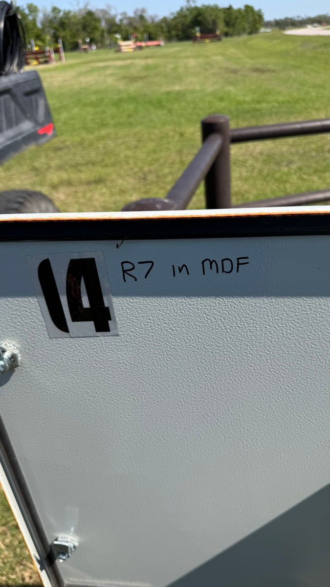 A grey IDF cabinet standing in a grass field, labeled '14' with 'R7 in MDF' written beside it in marker.