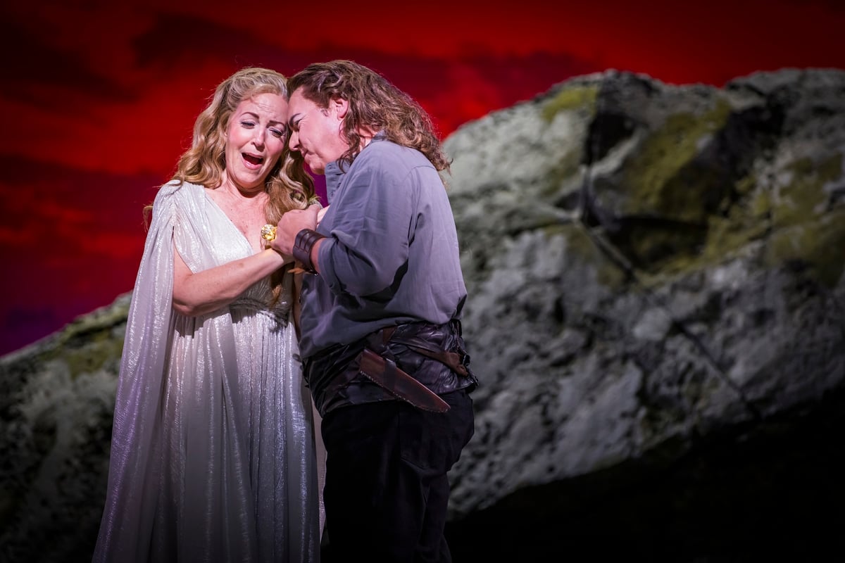 Brünnhilde and Siegfried embrace on the rock beneath a blood-red sky.