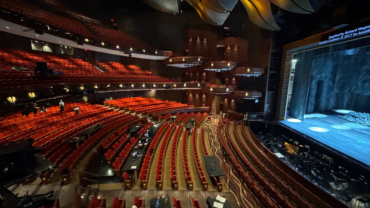 Wide view of the empty Cobb Energy auditorium from the lighting booth, with 'Siegfried by Richard Wagner' English captions projected on the closed curtain