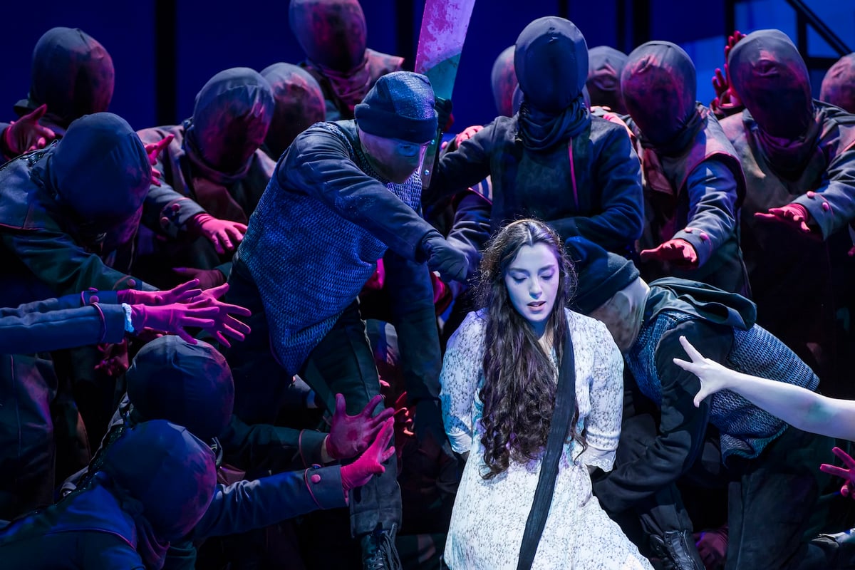 Juliana Grigoryan as Liù in a white dress, center, surrounded by the masked, hooded chorus in The Atlanta Opera production of Turandot
