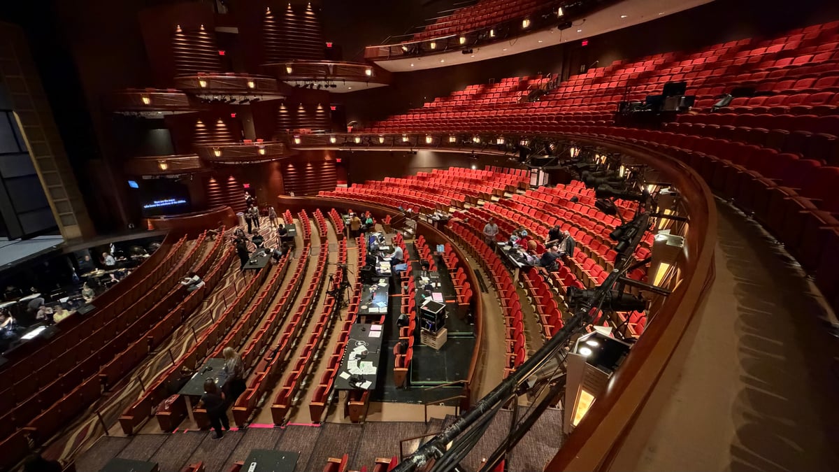 View from the balcony of the Cobb Energy auditorium before Turandot tech, tiered red seating and the orchestra pit setup visible