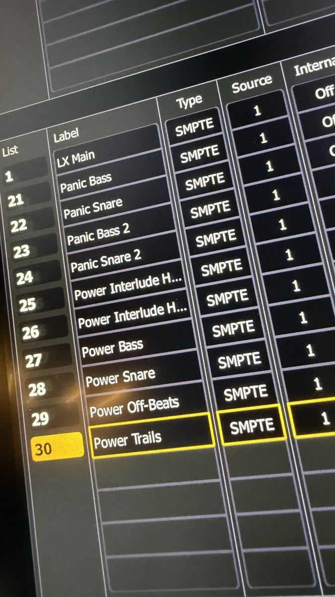 A close-up of the console's SMPTE timecode event list, cue lists labeled 'LX Main,' 'Power Bass,' and 'Power Trails' among others, showing the show run to timecode.