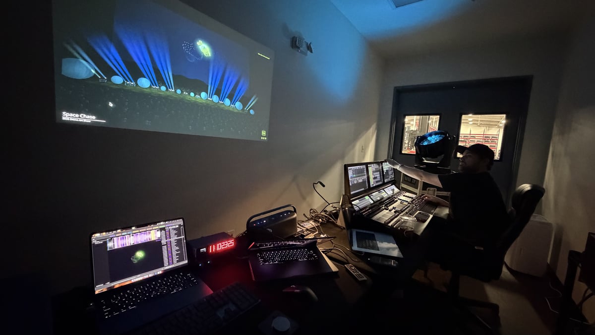 A previs session in the studio, the show projected on the wall beside the consoles.