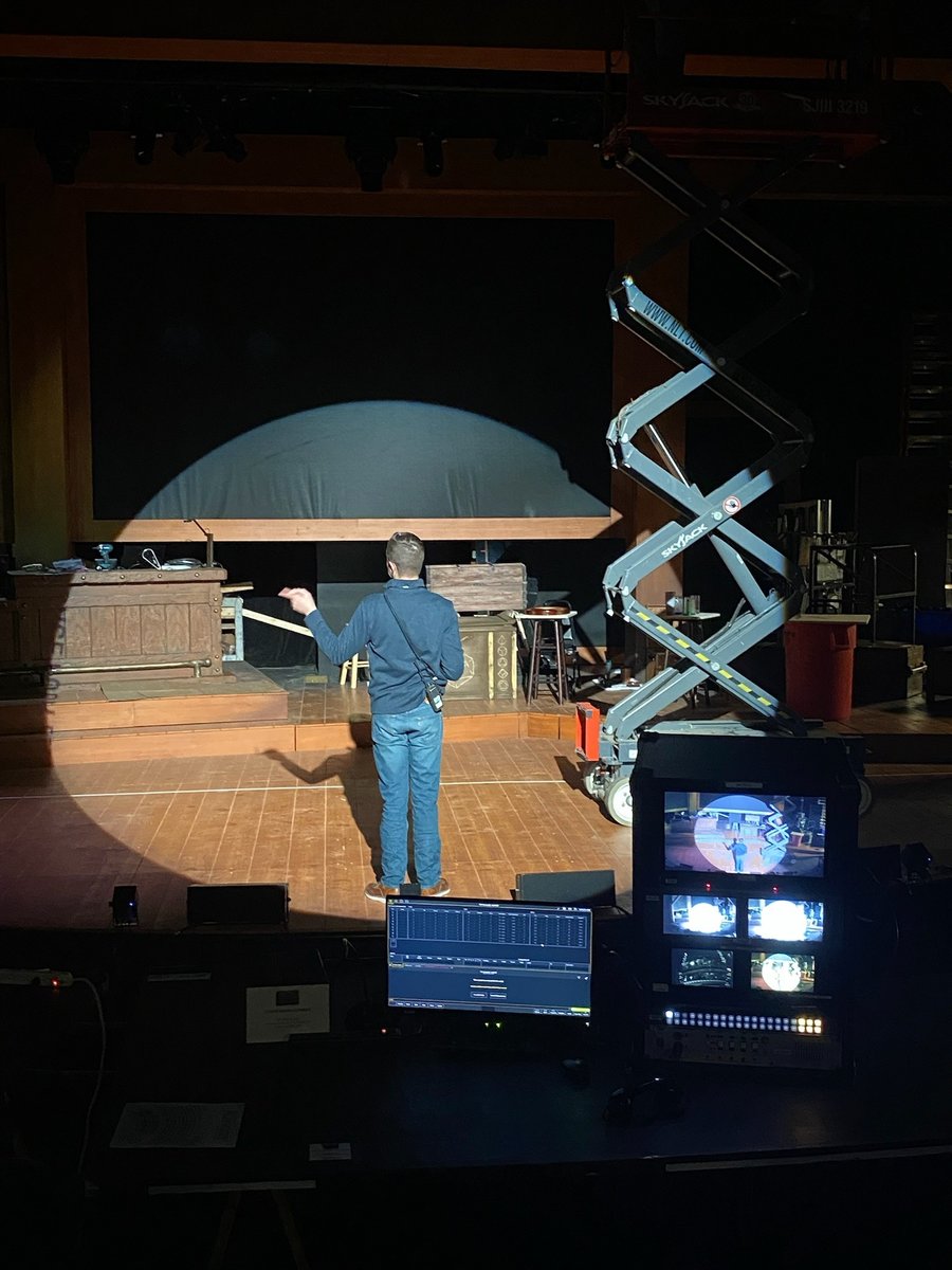 A scissor lift onstage during load-in, with a tech monitor in the foreground.