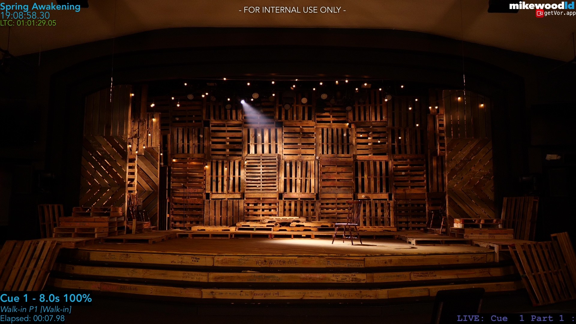 The same set in the warm amber walk-in look, a single textured beam raking the center of the stage