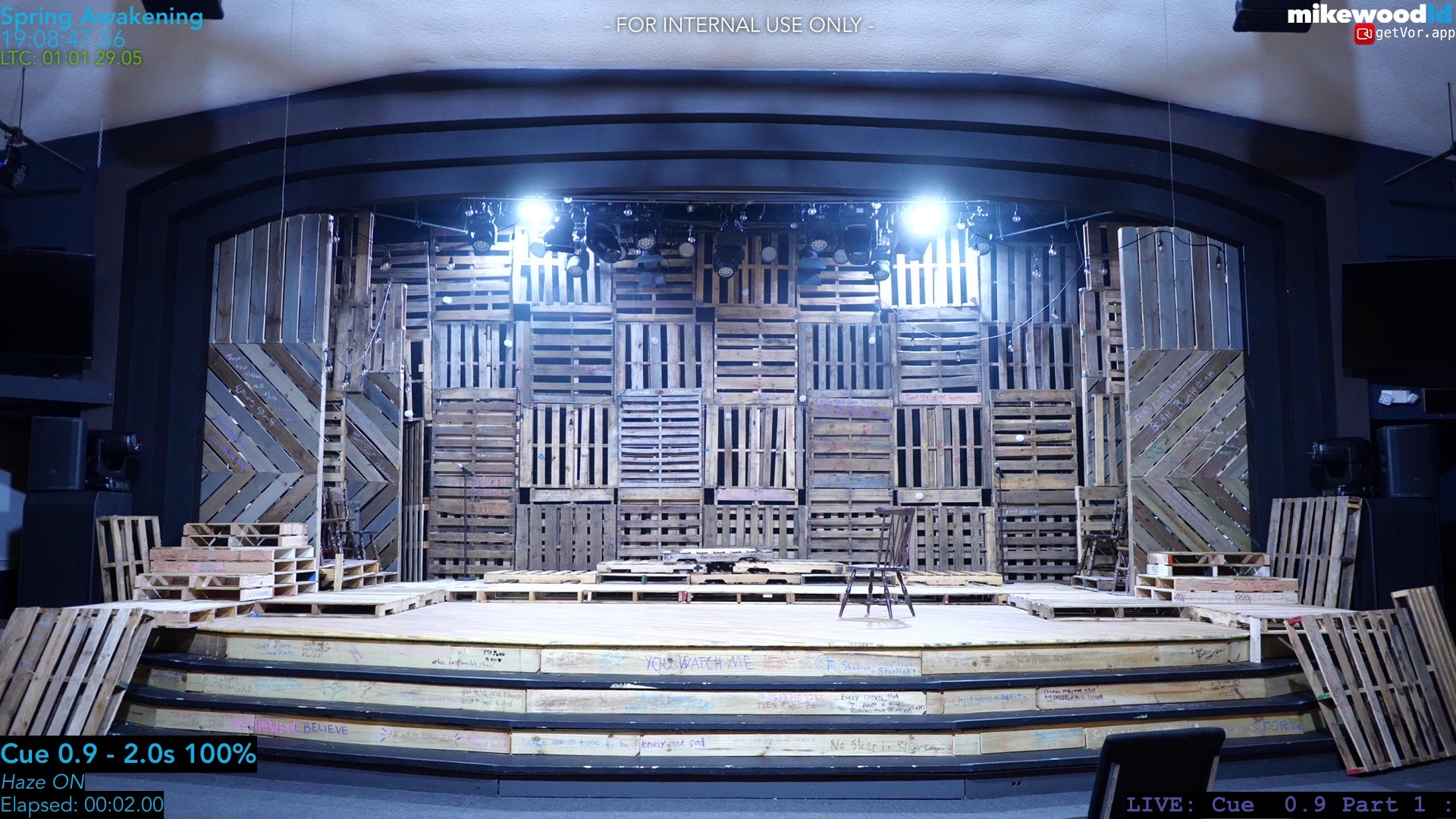 The Spring Awakening pallet-wall set and thrust under cool blue work light, haze hanging in the air, stage empty