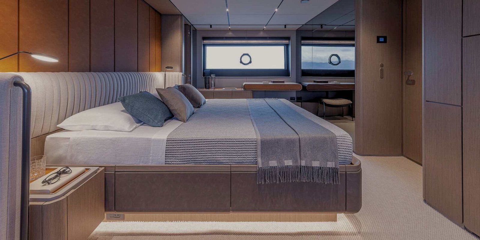 Cabina matrimoniale sul ponte inferiore del Ferretti Infynito 90, con un ampio letto, finestrature a scafo e una scrivania