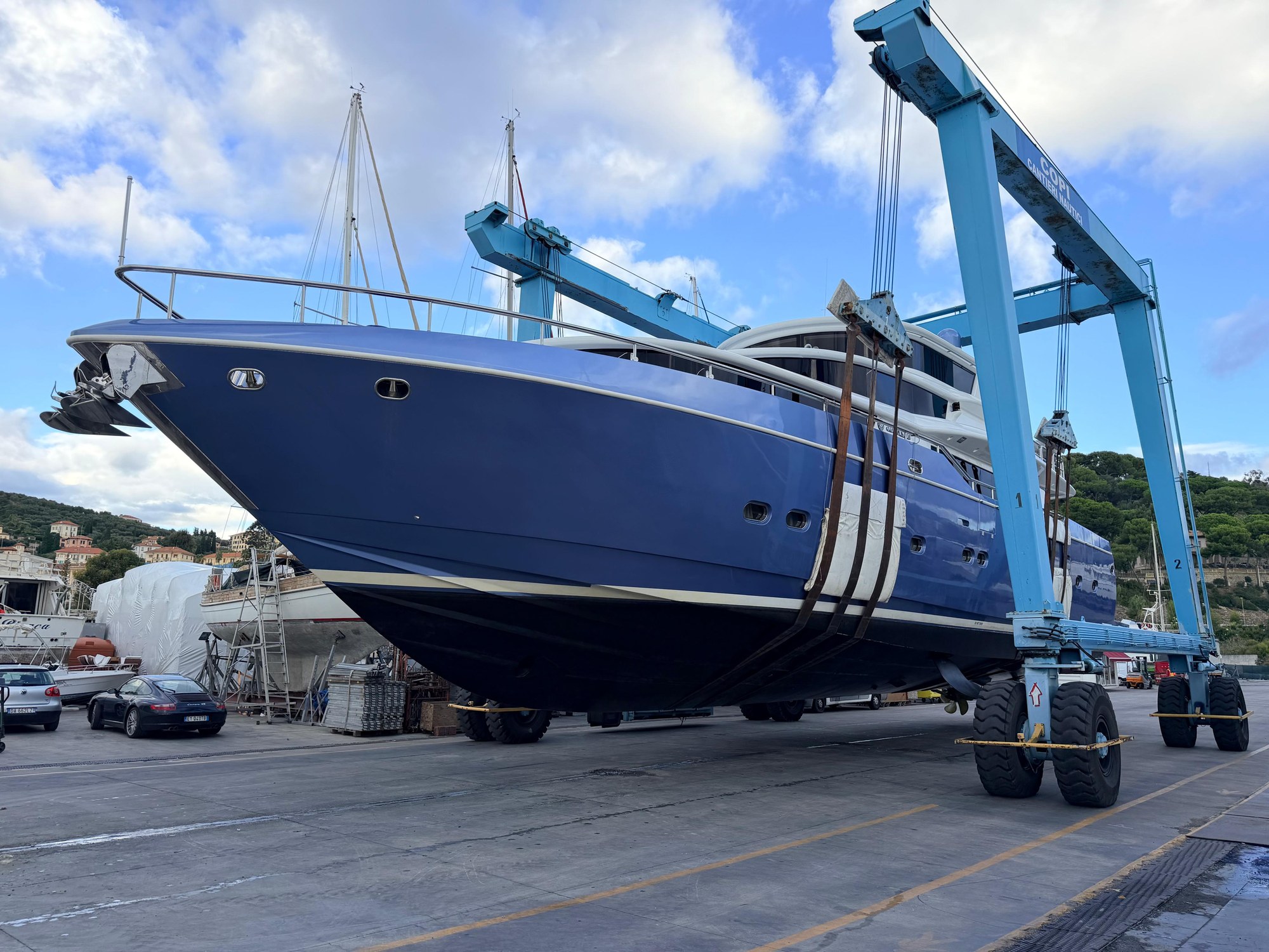 M/Y Daylight, a blue-hulled motor yacht, held in the slings of the 130-ton travel lift on the hardstand at Copi Cantieri Nautici in Imperia
