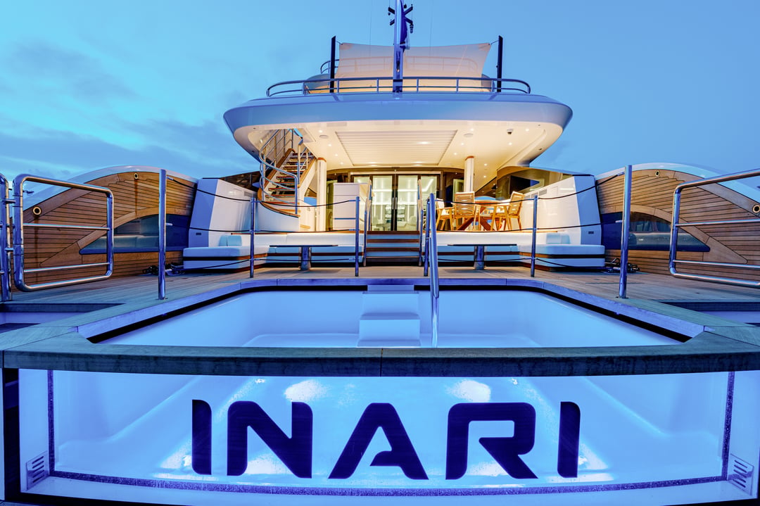 Oasis Deck stern of M/Y Inari at night with illuminated name and pool
