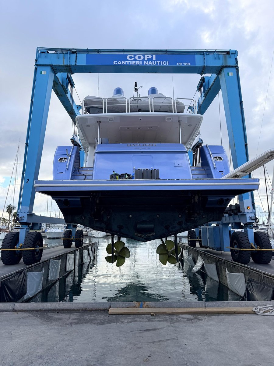 M/Y Daylight raised clear of the water in the slings of the travel lift, with her twin propellers and the underside of her hull exposed