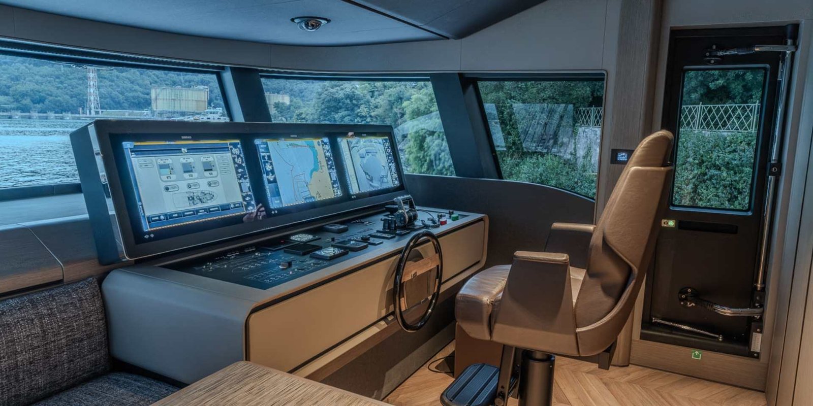 Plancia di comando del Ferretti Infynito 90, con tre display di navigazione, poltrona di pilotaggio e ampie vetrate