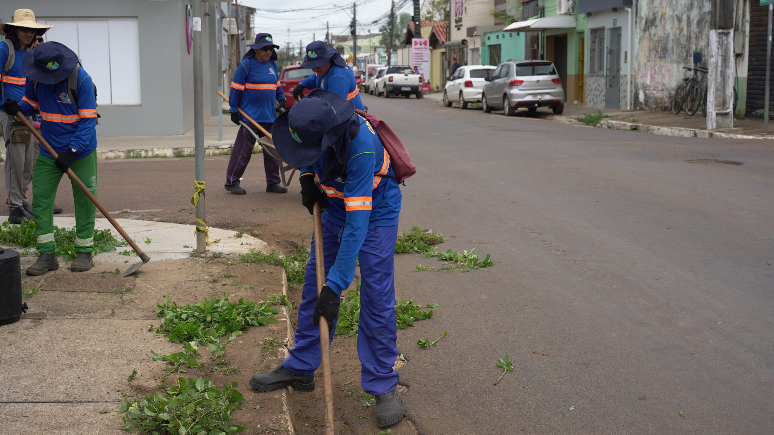 Equipe de manutenção urbana realizando capina e limpeza de vias em ambiente urbano brasileiro