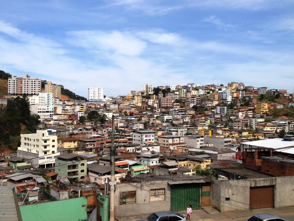 Vista urbana de Viçosa (MG) com morros ao fundo e céu parcialmente nublado