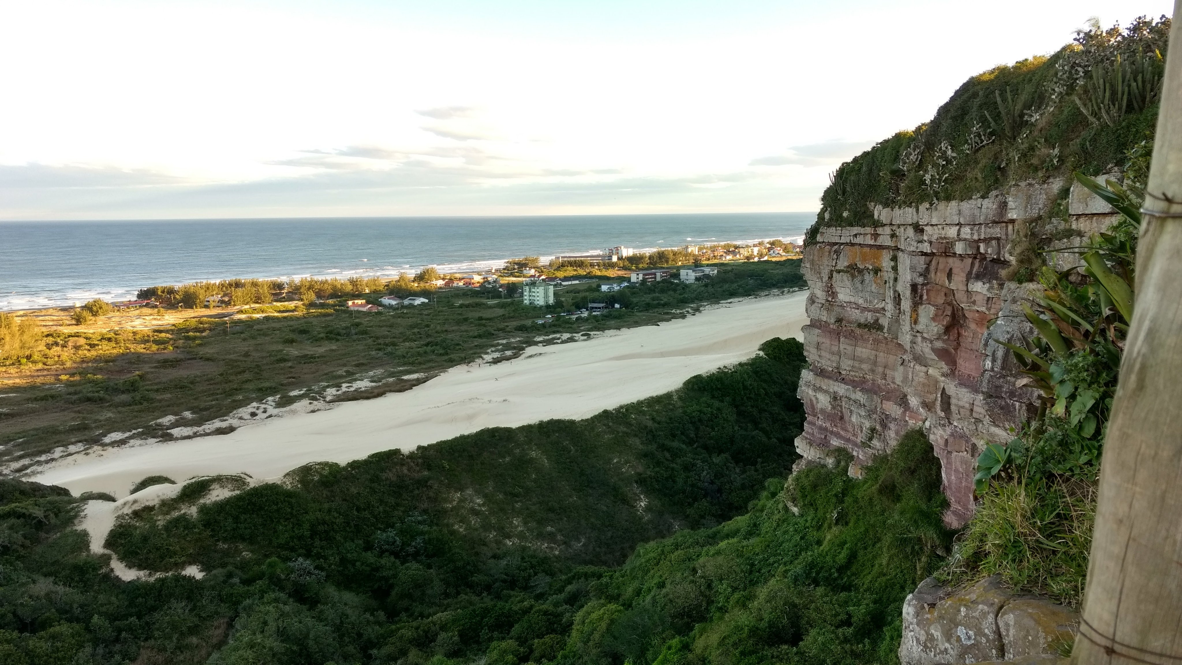 Vista aérea de Araranguá SC ao entardecer, com morros e litoral ao fundo