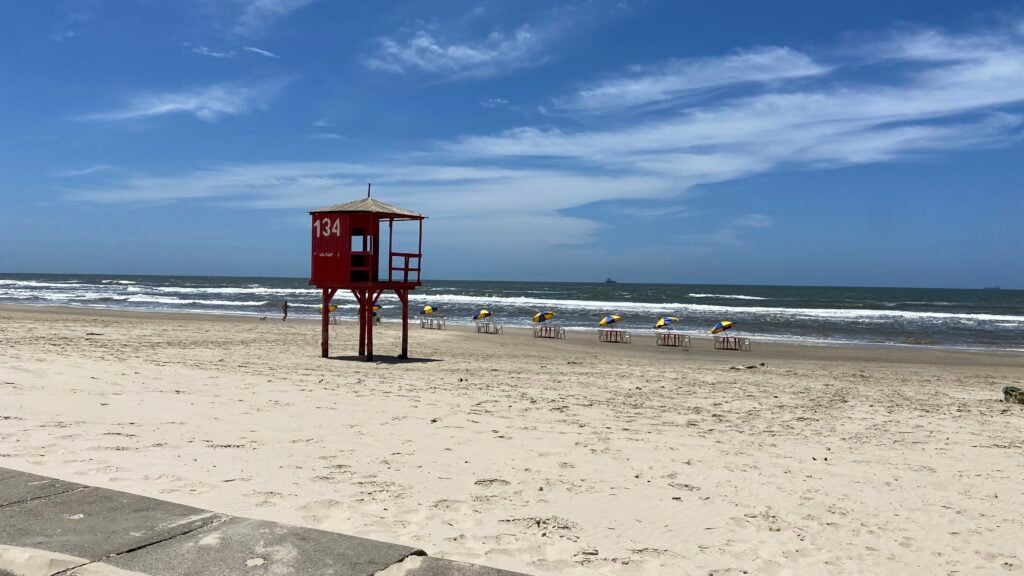 Orla urbana de Imbé ao entardecer, com praia, mar e área urbana ao fundo