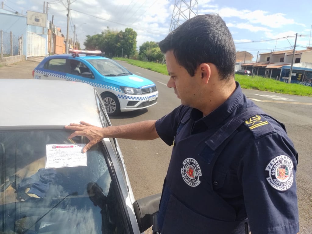 Agente da Guarda Municipal de Americana (GAMA) ao lado de viatura, em patrulhamento urbano