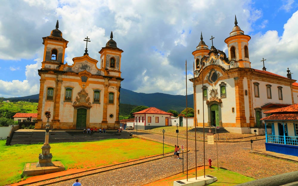 Vista de cidade do interior da Bahia, com igreja e casario colorido, céu azul e vegetação ao fundo
