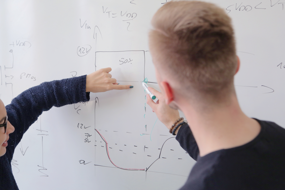 Professor explicando fórmulas no quadro em ambiente universitário