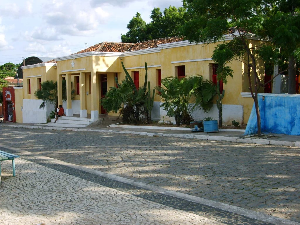Rua do interior do Ceará, comércio local e serras ao fundo, fim de tarde