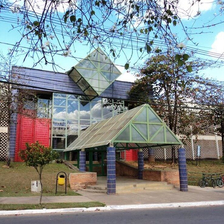 Campus da UFV com edifício moderno, áreas verdes e bicicletas estacionadas em dia ensolarado