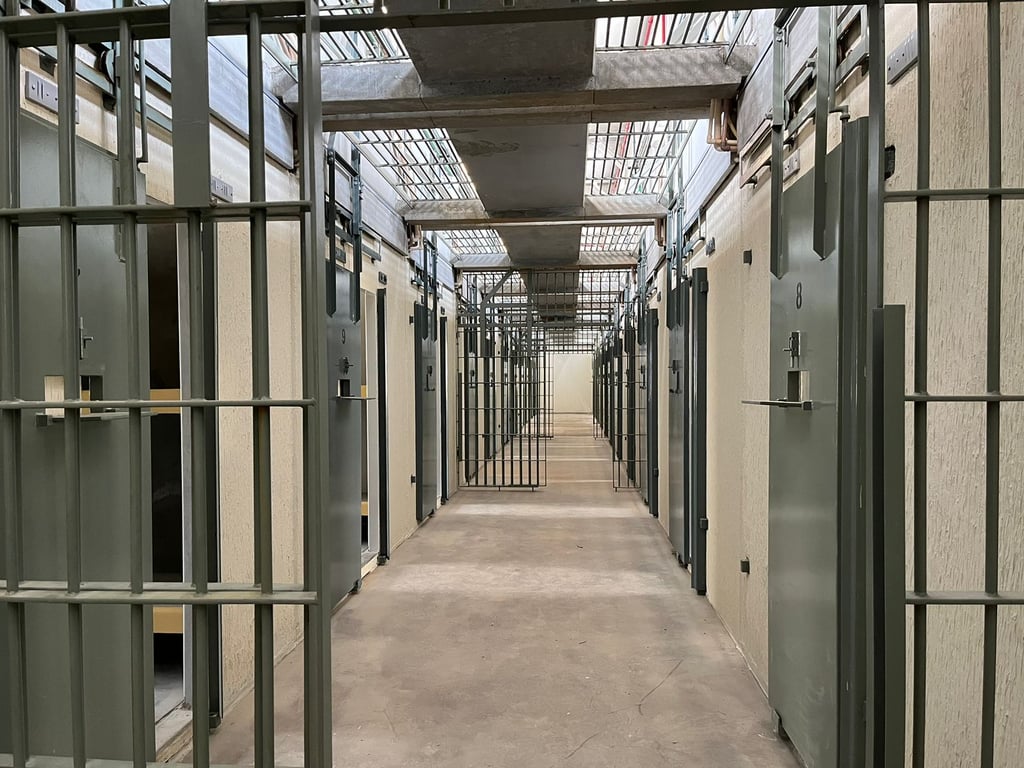 Corredor de unidade prisional, com celas vazias e iluminação natural; imagem ilustrativa do ambiente carcerário