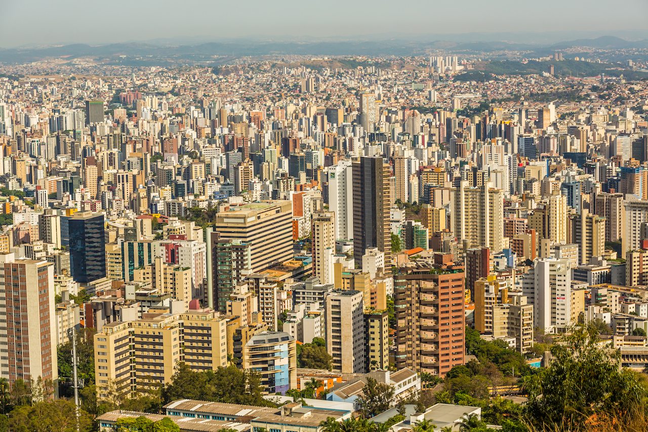 Vista aérea de Belo Horizonte ao entardecer, com montanhas ao fundo