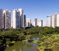 Vista aérea de Goiânia, com prédios modernos e áreas verdes ao entardecer.