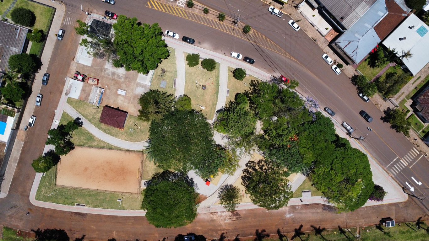 Vista aérea da praça central de Santa Bárbara do Sul (RS), com áreas verdes e caminhos sinuosos