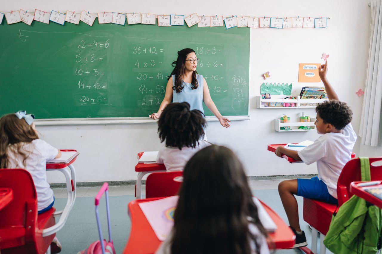 Professor explica conteúdo de matemática em sala de aula, estudantes atentos