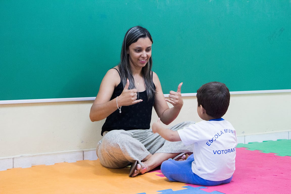 Sala de aula inclusiva, com professor e estudante, em ambiente educacional no Brasil