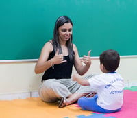Sala de aula inclusiva, com professor e estudante, em ambiente educacional no Brasil.
