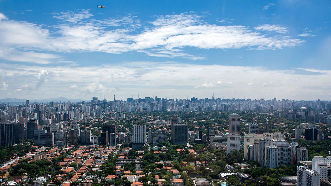 Vista urbana com áreas verdes e prédios sob céu parcialmente nublado