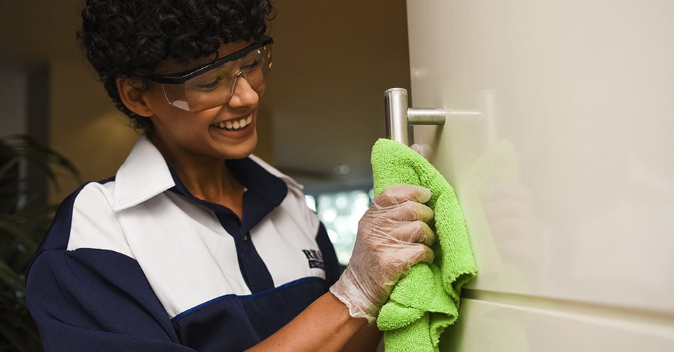 Profissional de serviços gerais realizando limpeza em ambiente corporativo