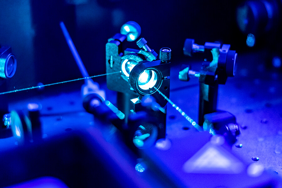 Conceito visual de fotônica em laboratório, com feixes de luz e equipamentos ópticos de precisão
