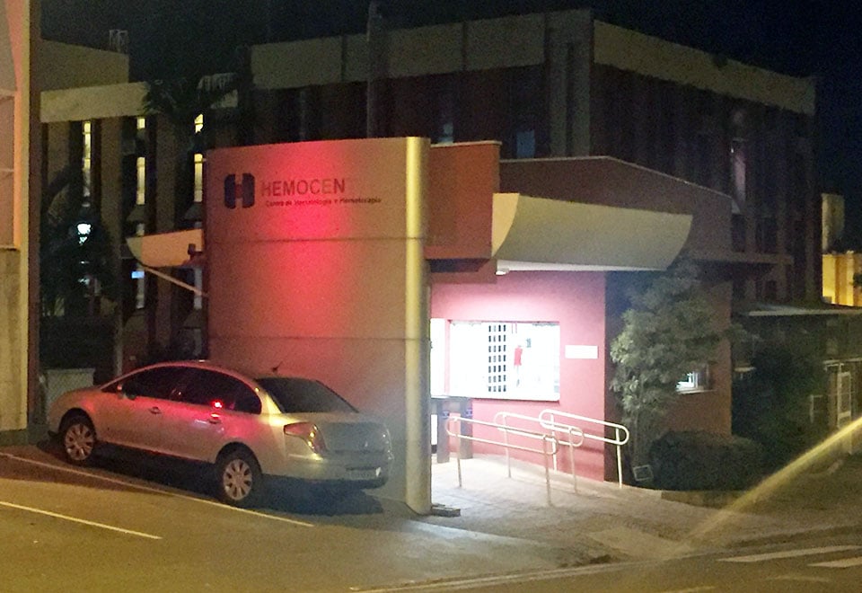 Fachada do Hemocentro da Unicamp à noite, com veículo estacionado; cena institucional em área hospitalar