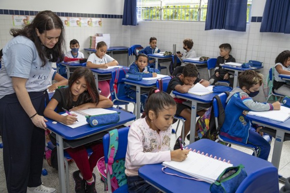 Sala de aula em escola pública do interior de São Paulo, com alunos e professora em atividade, ambiente iluminado e organizado