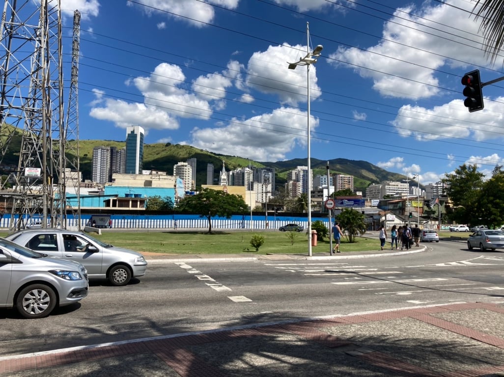 Paisagem urbana de Nova Iguaçu RJ, com prédios e montanhas ao fundo ao entardecer