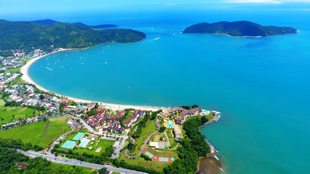 Vista aérea da orla de Caraguatatuba, no Litoral Norte de SP, com mar, cidade e Serra do Mar ao fundo