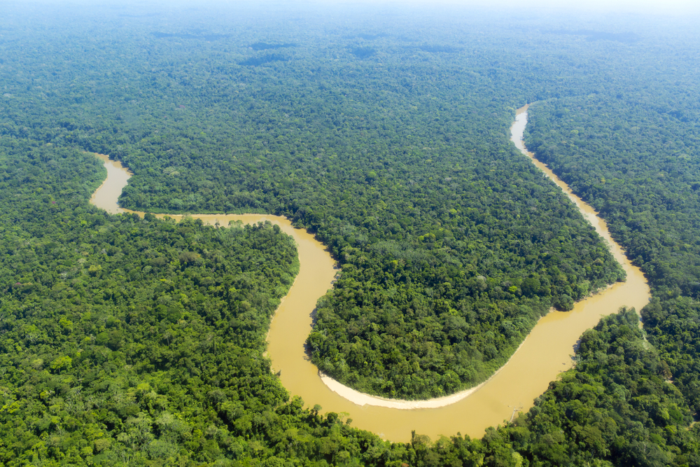 Vista aérea de região amazônica com rio sinuoso e grande área verde sob céu claro