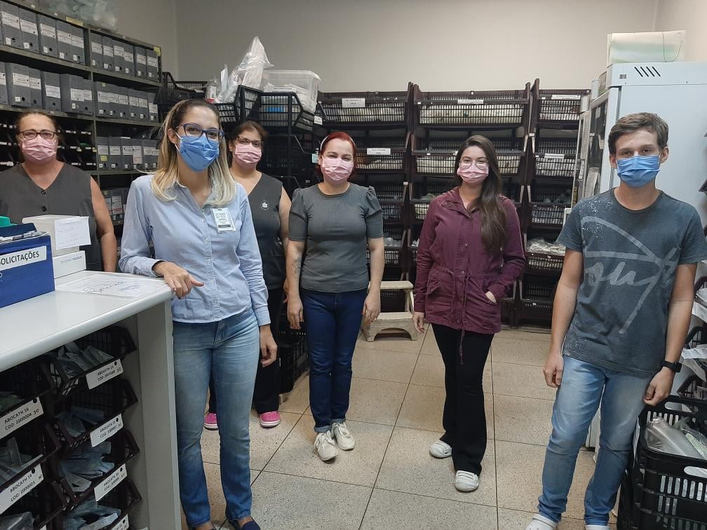 Ambiente de farmácia hospitalar com profissionais organizando medicamentos