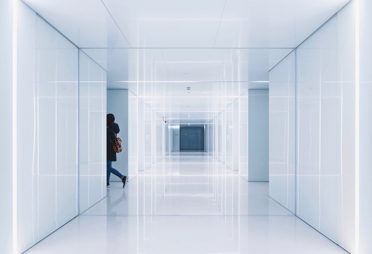 Equipe de limpeza em corredor de prédio público com carrinho e placa de piso molhado