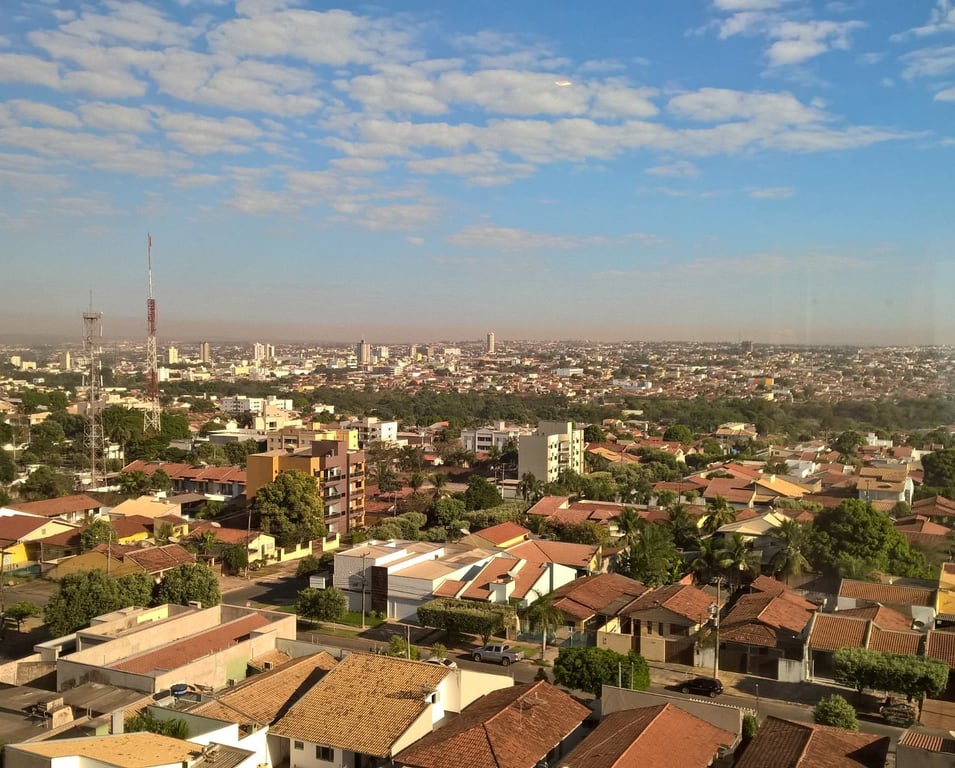 Vista aérea de cidade média do interior ao pôr do sol, com avenida, casas e árvores