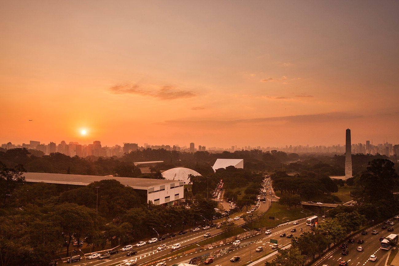 Fachada do MAC USP no fim de tarde, com skyline de São Paulo ao fundo